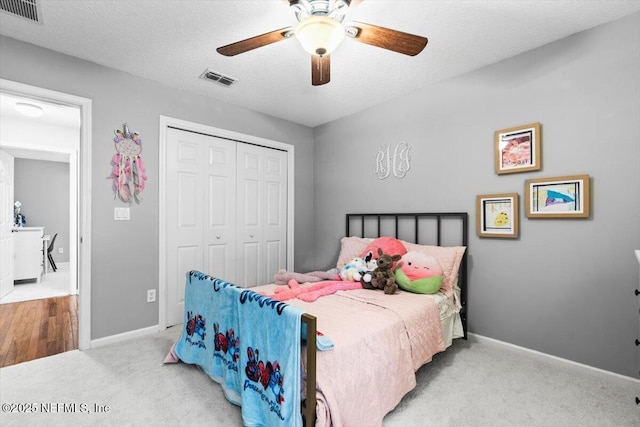 bedroom with baseboards, visible vents, carpet floors, a closet, and a textured ceiling