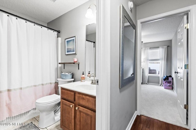 full bathroom featuring baseboards, a textured ceiling, vanity, and toilet