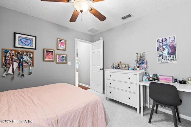 bedroom with visible vents, light colored carpet, a ceiling fan, and a textured ceiling