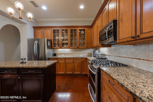 3808 Catania Pl, Jacksonville, FL 32224 - kitchen featuring tasteful backsplash, visible vents, ornamental molding, brown cabinets, and stainless steel appliances
