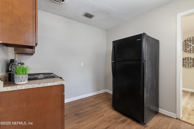 kitchen featuring visible vents, wood finished floors, light countertops, and freestanding refrigerator