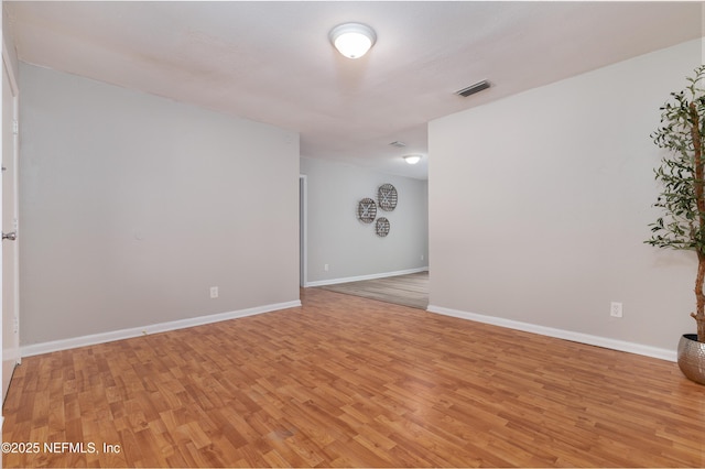 empty room with visible vents, light wood-style flooring, and baseboards