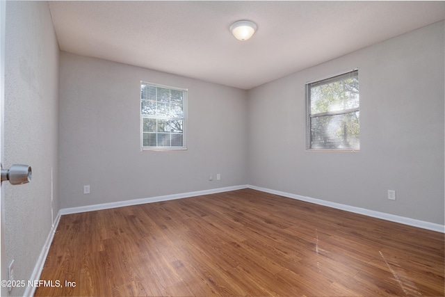 spare room featuring baseboards and wood finished floors