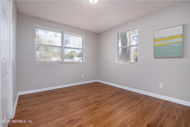 unfurnished room with baseboards and wood finished floors