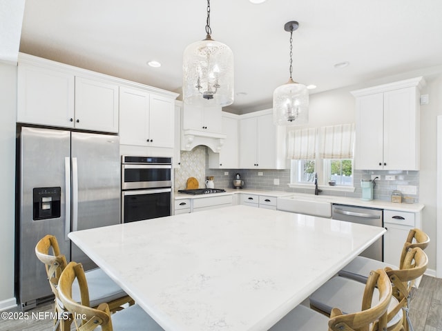 kitchen with appliances with stainless steel finishes, white cabinetry, a kitchen breakfast bar, and a sink