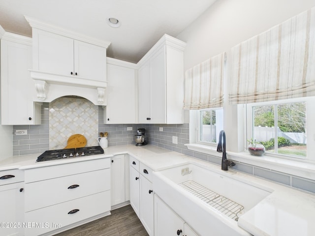 kitchen featuring a sink, backsplash, stainless steel gas stovetop, and light countertops