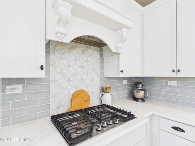 kitchen featuring premium range hood, tasteful backsplash, white cabinetry, light stone countertops, and stainless steel gas cooktop
