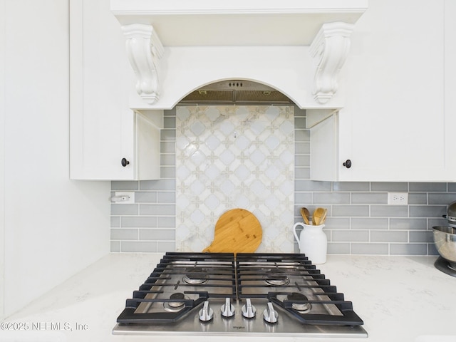 details with stainless steel gas cooktop, decorative backsplash, and white cabinetry