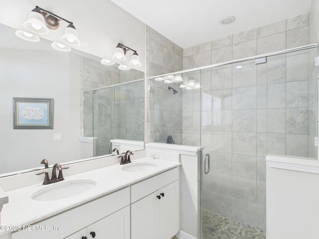 bathroom featuring double vanity, a stall shower, and a sink