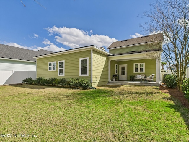 rear view of house with fence and a lawn