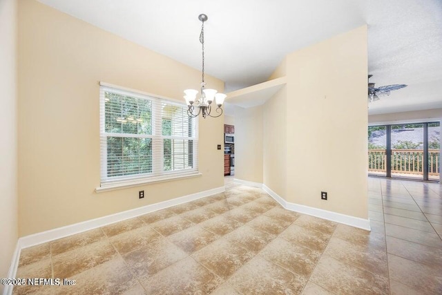 unfurnished room featuring baseboards, a wealth of natural light, and a chandelier