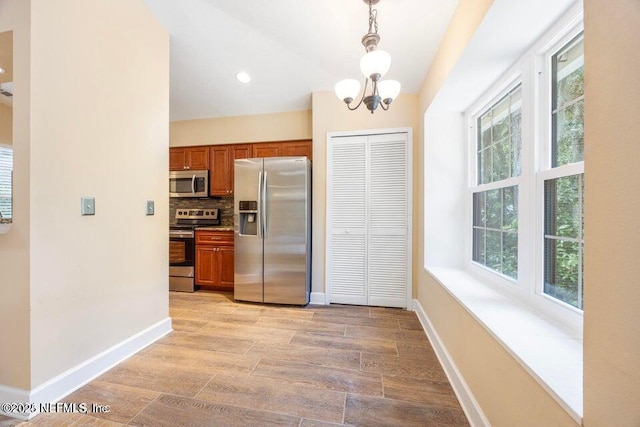 kitchen with baseboards, brown cabinets, hanging light fixtures, appliances with stainless steel finishes, and tasteful backsplash