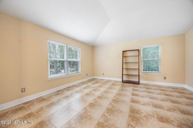 unfurnished room featuring baseboards and vaulted ceiling