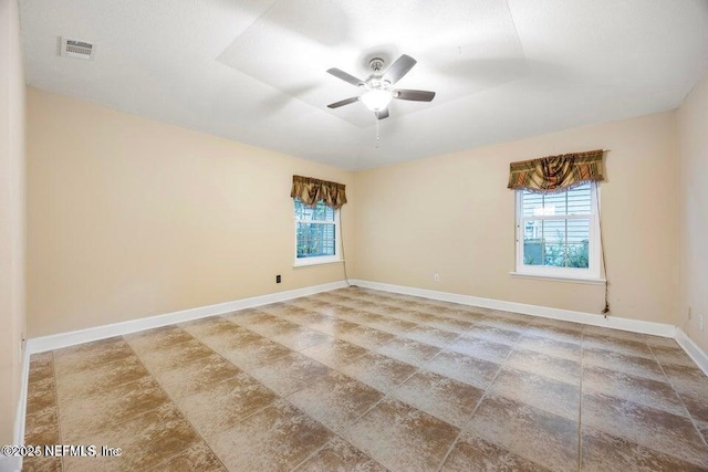 unfurnished room featuring visible vents, ceiling fan, a tray ceiling, and baseboards