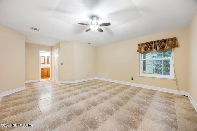 spare room with visible vents, baseboards, a tray ceiling, and a ceiling fan