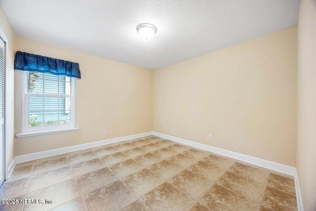 spare room featuring a textured ceiling and baseboards