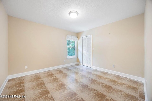 unfurnished room featuring baseboards and a textured ceiling