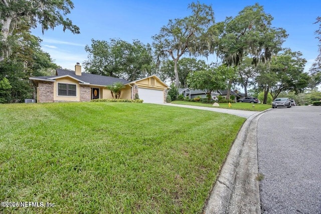 single story home with a front yard, an attached garage, concrete driveway, and a chimney