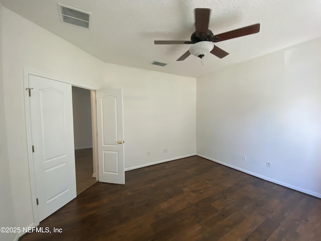 spare room featuring visible vents, dark wood-type flooring, ceiling fan, and a textured ceiling