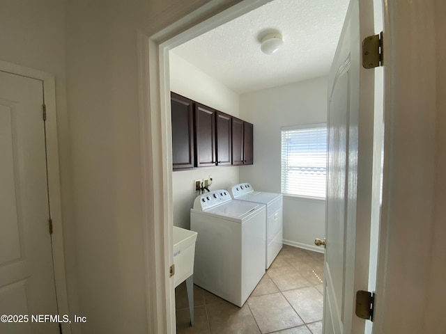 laundry area with baseboards, washing machine and dryer, light tile patterned floors, cabinet space, and a textured ceiling