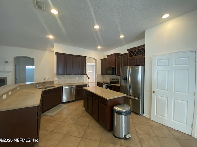 kitchen featuring arched walkways, visible vents, appliances with stainless steel finishes, and a sink