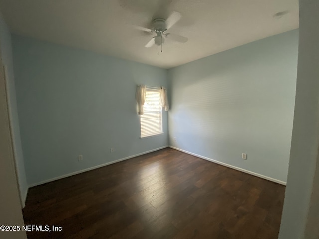 spare room with dark wood finished floors, baseboards, and ceiling fan