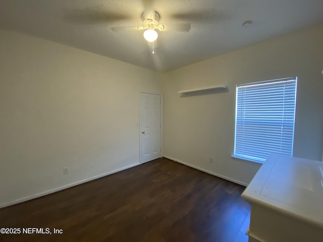 spare room with dark wood-style floors, baseboards, and a ceiling fan