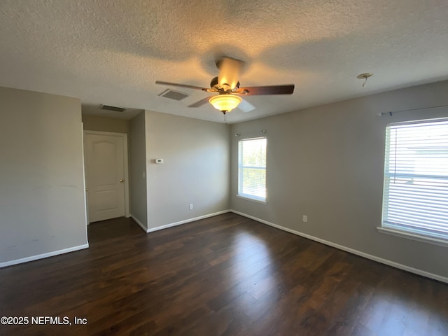 empty room featuring visible vents, dark wood-style floors, and ceiling fan