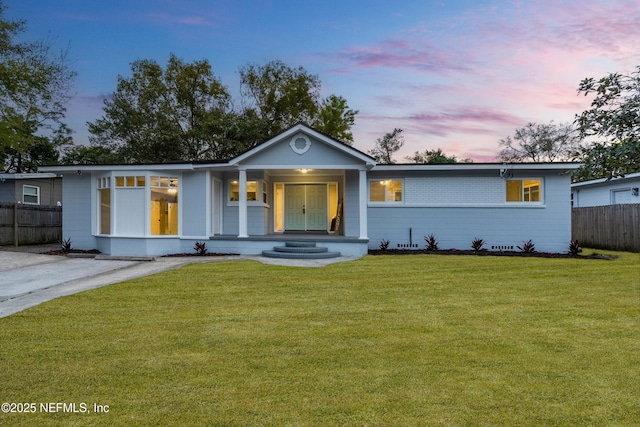 ranch-style home featuring a yard and fence