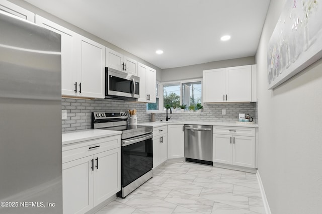 kitchen featuring marble finish floor, white cabinetry, stainless steel appliances, and light countertops