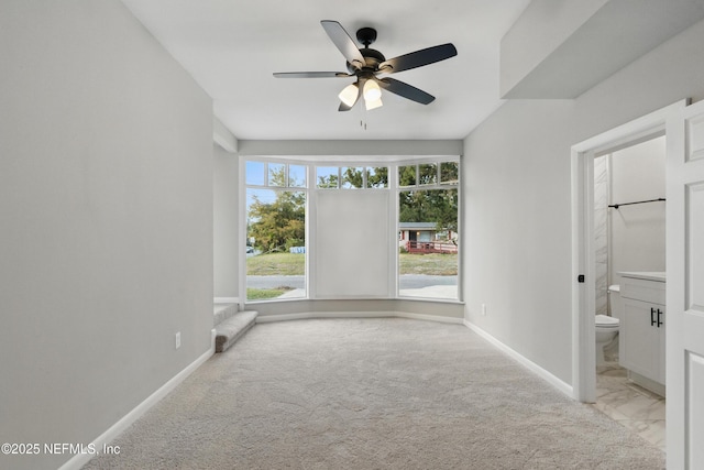 carpeted empty room featuring baseboards and a ceiling fan