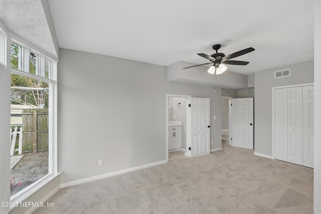 unfurnished bedroom with visible vents, a closet, baseboards, light colored carpet, and ceiling fan