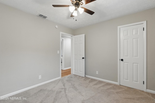 unfurnished bedroom with visible vents, carpet flooring, a textured ceiling, and baseboards