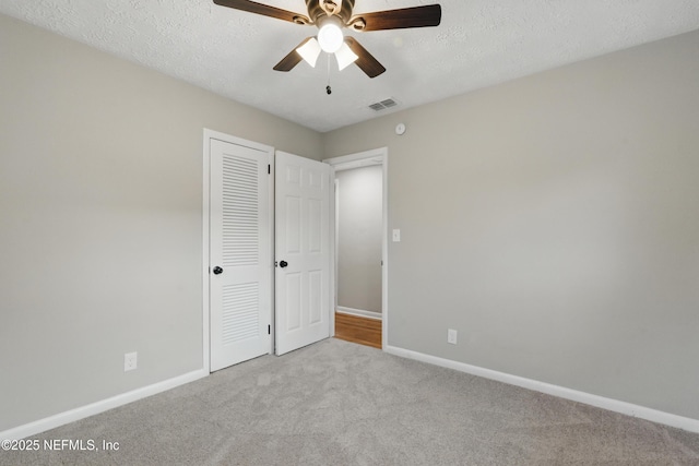 unfurnished bedroom featuring carpet flooring, baseboards, visible vents, and a textured ceiling