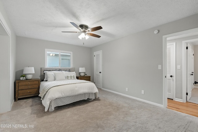 bedroom featuring baseboards, light carpet, a textured ceiling, and a ceiling fan