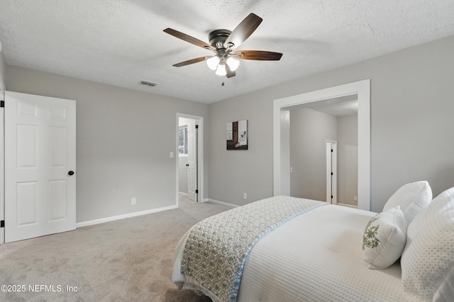 bedroom with visible vents, a textured ceiling, baseboards, light colored carpet, and ceiling fan