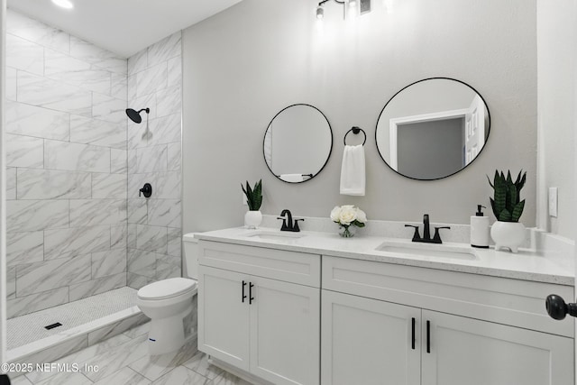 bathroom featuring double vanity, marble finish floor, a tile shower, and a sink