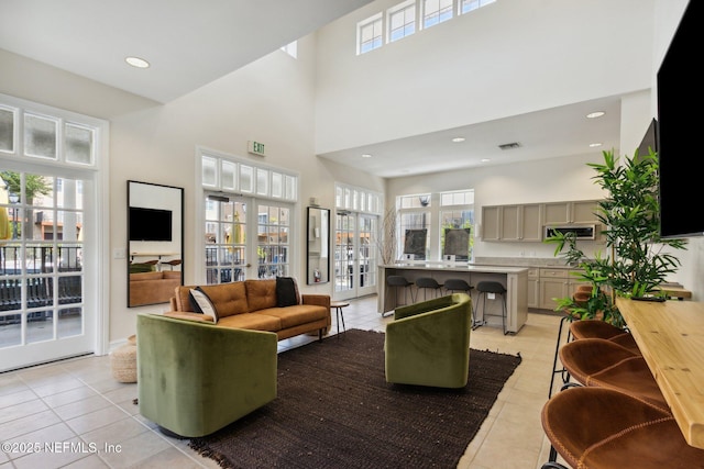 living area with light tile patterned flooring, recessed lighting, visible vents, and a towering ceiling