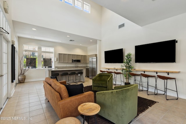 living area with visible vents, baseboards, light tile patterned floors, recessed lighting, and a high ceiling