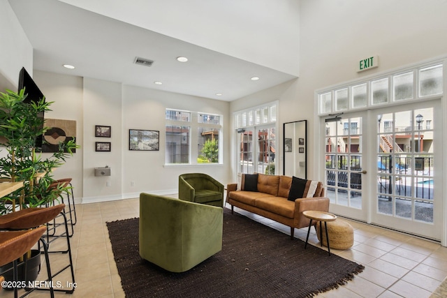 living area featuring visible vents, baseboards, recessed lighting, a towering ceiling, and light tile patterned flooring