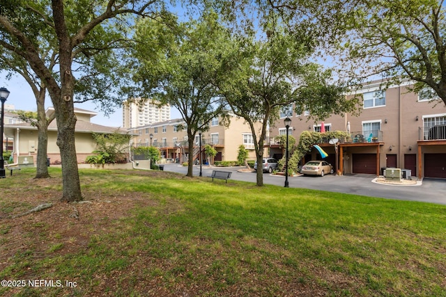 view of community featuring a lawn, an attached garage, and driveway