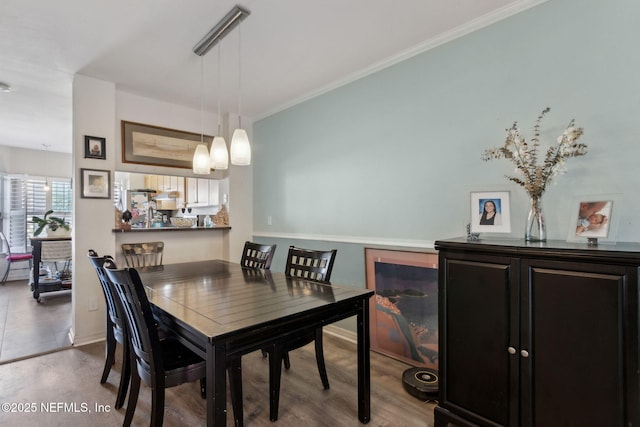 dining space featuring crown molding, wood finished floors, and baseboards