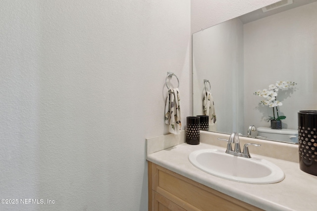 bathroom with visible vents, toilet, and vanity