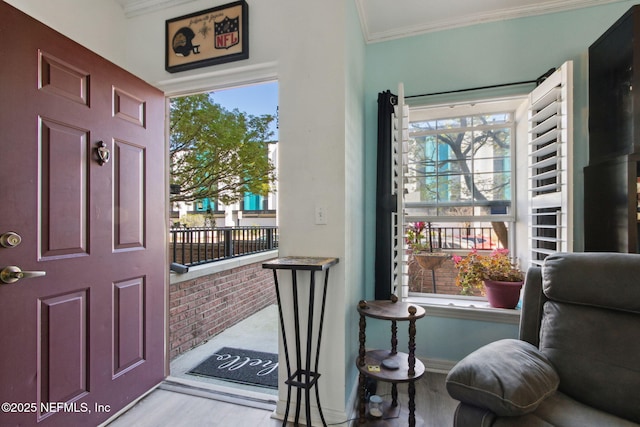 foyer with wood finished floors, a healthy amount of sunlight, and ornamental molding