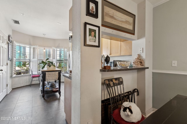 hall featuring tile patterned flooring, baseboards, and visible vents