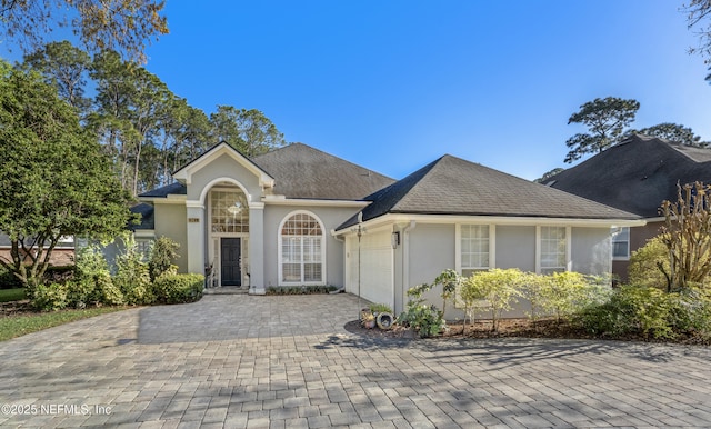 single story home featuring stucco siding, a shingled roof, decorative driveway, and a garage