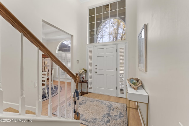 foyer with stairway, baseboards, wood finished floors, and a towering ceiling