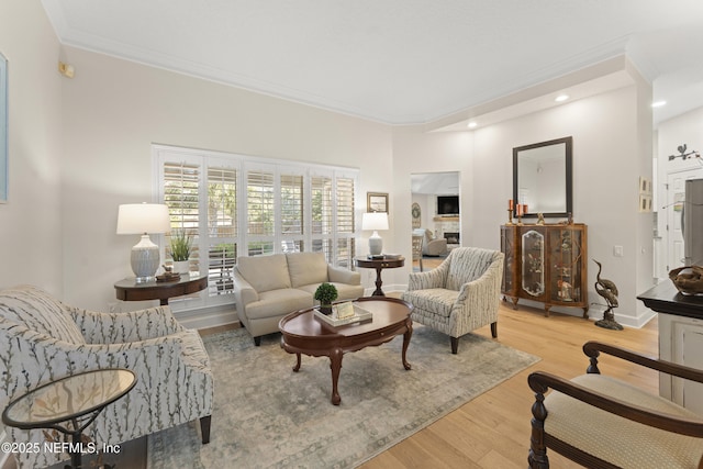 living room with recessed lighting, baseboards, ornamental molding, and light wood finished floors