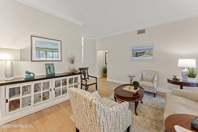 living area with visible vents, baseboards, ornamental molding, and light wood finished floors