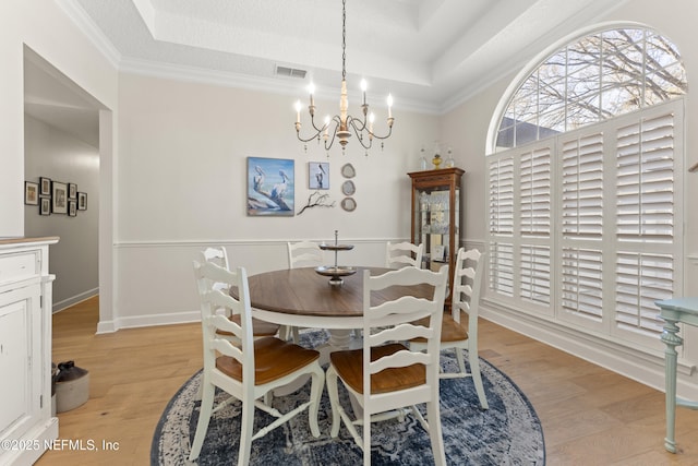 dining room featuring a tray ceiling, visible vents, light wood finished floors, and a chandelier